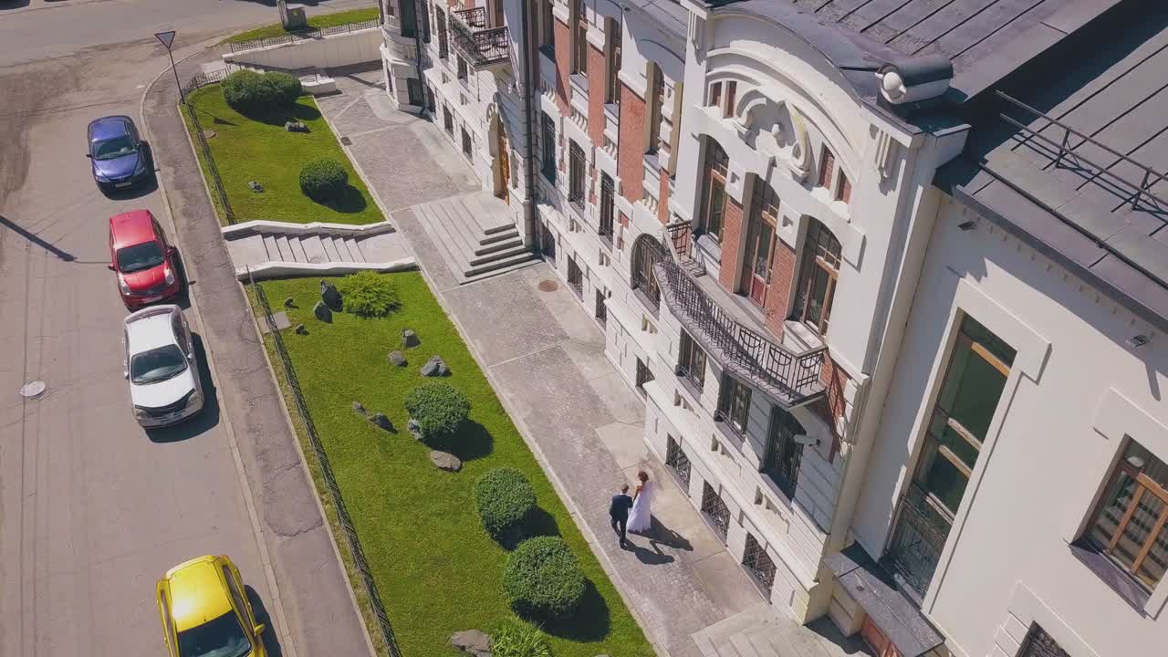 el novio y la novia caminan por la calle en un día soleado vista aérea