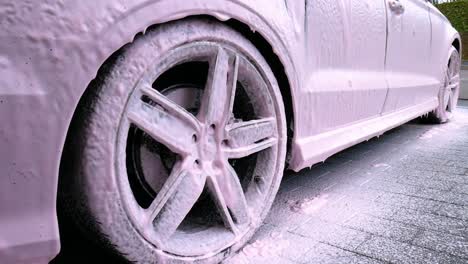 alloy wheel covered in pink snow foam dripping