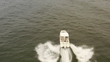 an aerial view of a small, white fishing boat speeding in the deep, green atlantic ocean by long island, ny