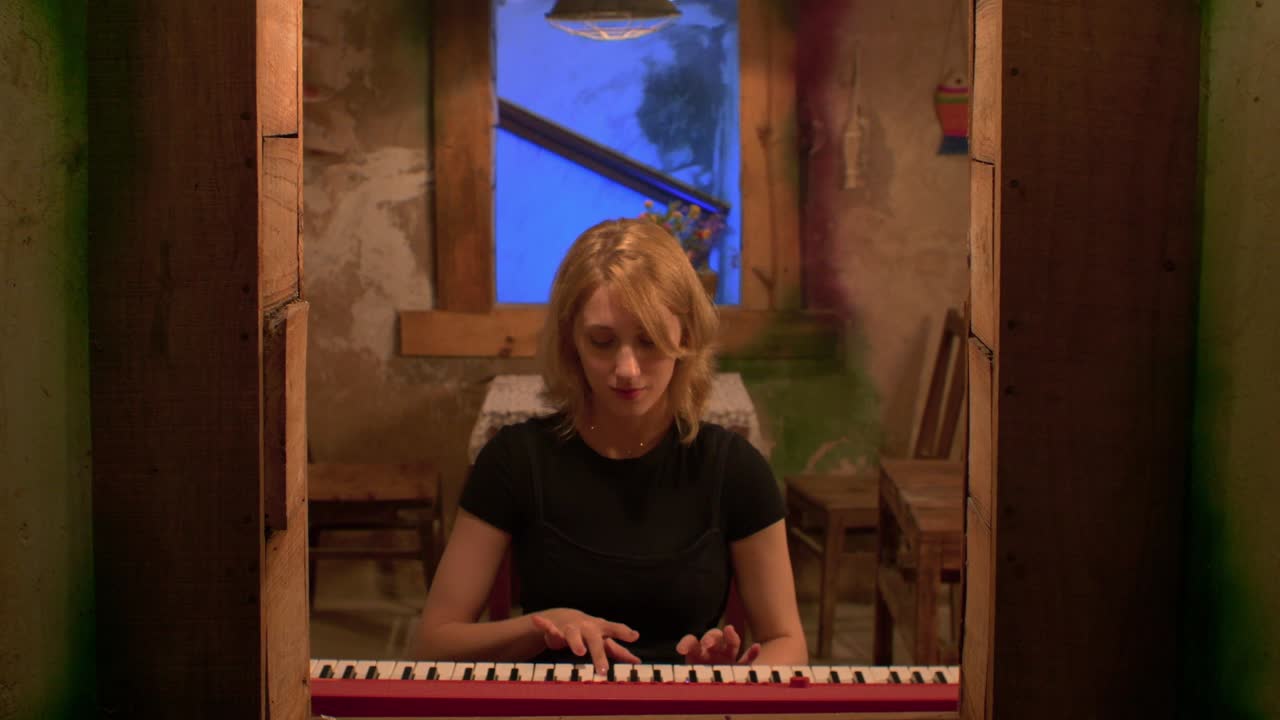 cámara lenta frente a la toma de una hermosa mujer tocando un piano rojo brillante en casa