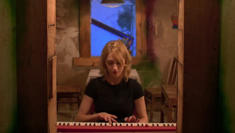 slow motion front on shot of a beautiful woman playing a bright red piano at home