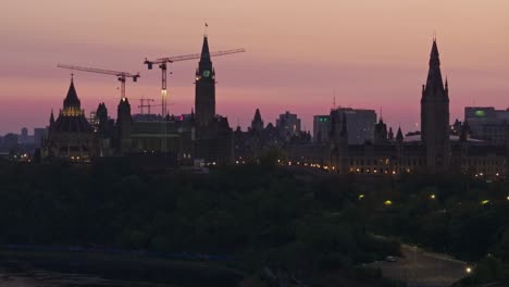 Tele-Drohnenvideo-Der-Kanadischen-Parlamentsgebäude-In-Ottawa,-Ontario,-Kanada-Bei-Sonnenaufgang,-Die-Gebäude-Zeichnen-Sich-Als-Silhouetten-Gegen-Den-Himmel-Ab