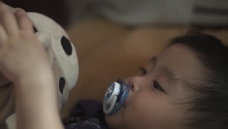 Malaysian-Toddler-with-Pacifier-Playing-with-Teddy-Bear,-Close-Up