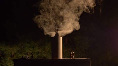 smoke coming out of a steel chimney at night in the norwegian village of arendel in zagorow, poland - close up