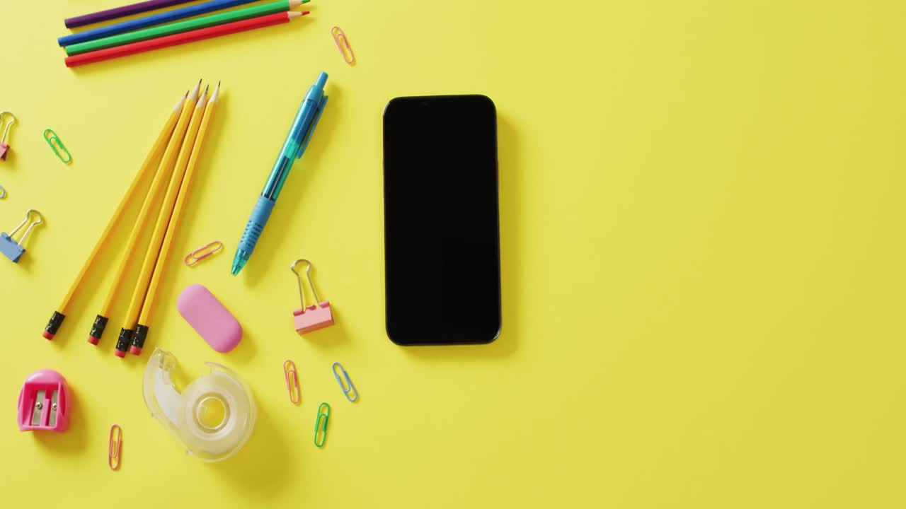 노란색 배경에 복사 공간을 가진 다양한 사무실 도구와 스마트 폰의 구성 비디오