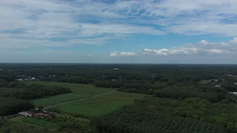 Aerial-panning-shot-of-Cu-Chi,-Vietnam-with-farms,-forests-on-sunny-day-with-blue-sky