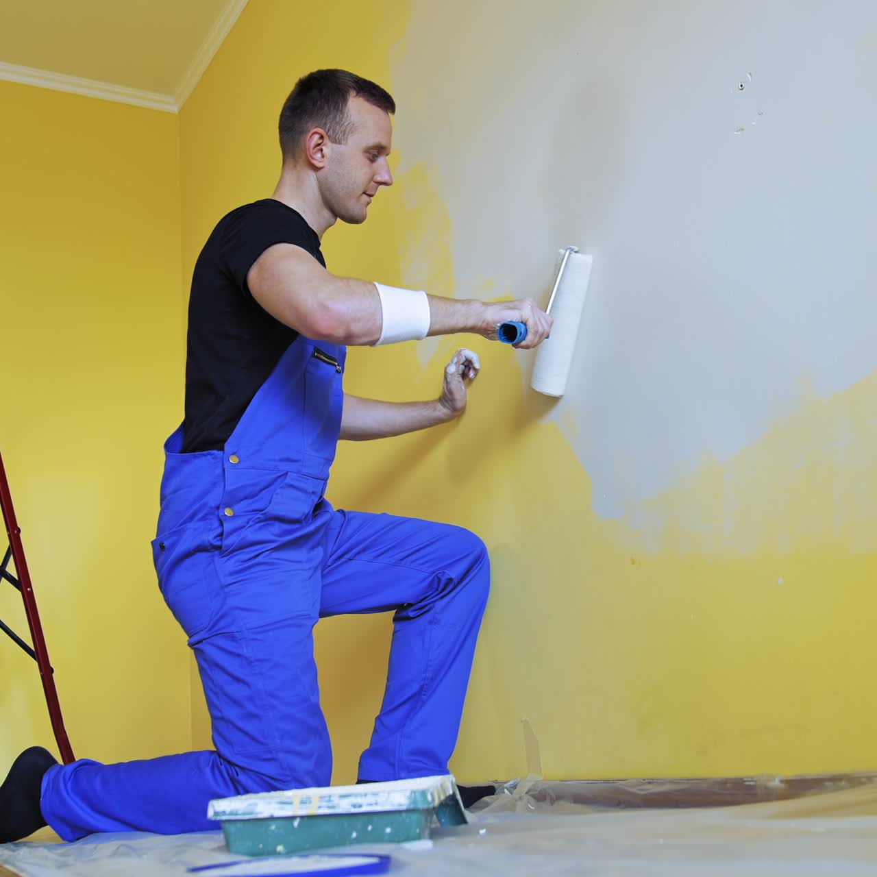 Attractive worker doing renovation wall. Professional painter with brush and roller decorating indoor of house