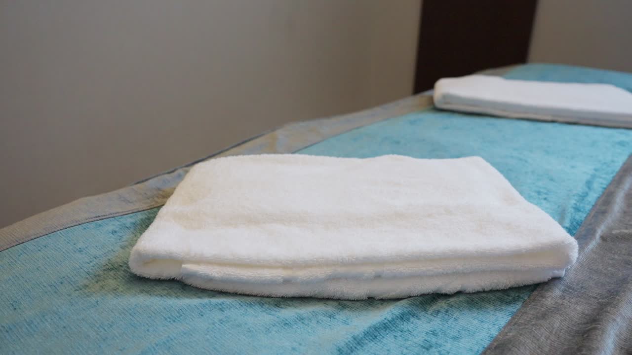 Hotel staff folding white towels on a bed