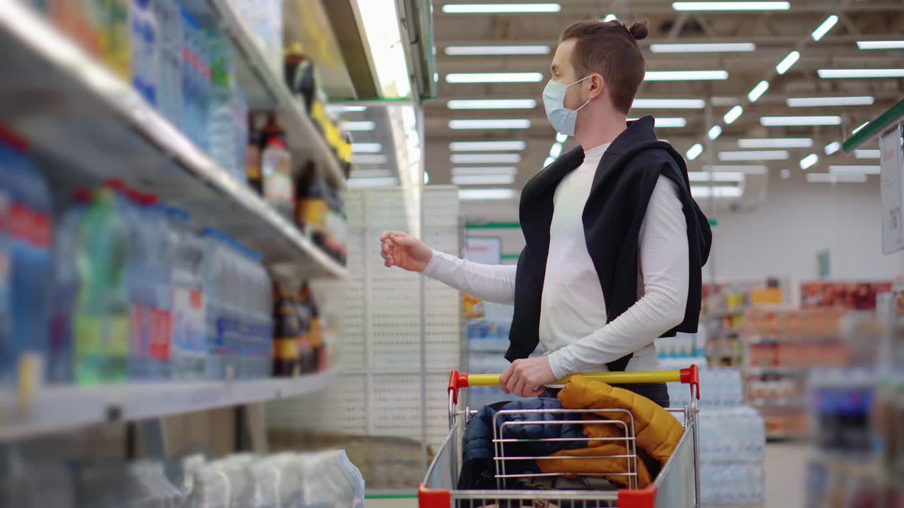 hombre comprando agua en un supermercado usando una máscara durante una pandemia