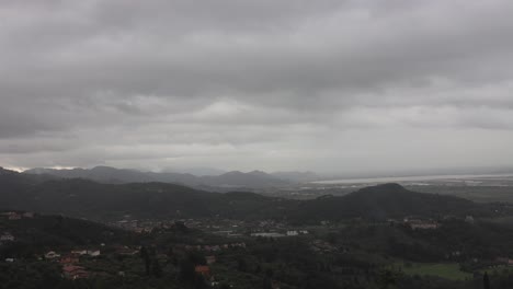 time lapse of overcast clouds and rain over rural hilly landscape and villages near via reggio, italy