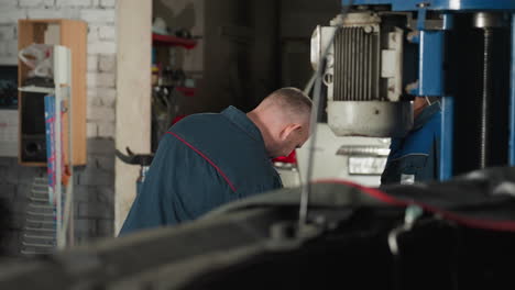 engineer in blue uniform working in mechanical shop, focused on task, with machinery and equipment in background, industrial setting with tools and organized workspace