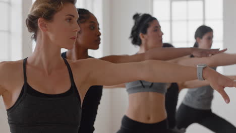 yoga class group of multiracial women practicing warrior pose enjoying healthy lifestyle exercising in fitness studio