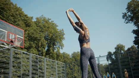 Rückansicht-Einer-Sportlichen-Frau,-Die-Sich-Auf-Dem-Basketballplatz-Im-Freien-Aufwärmt-Und-Zurückstreckt