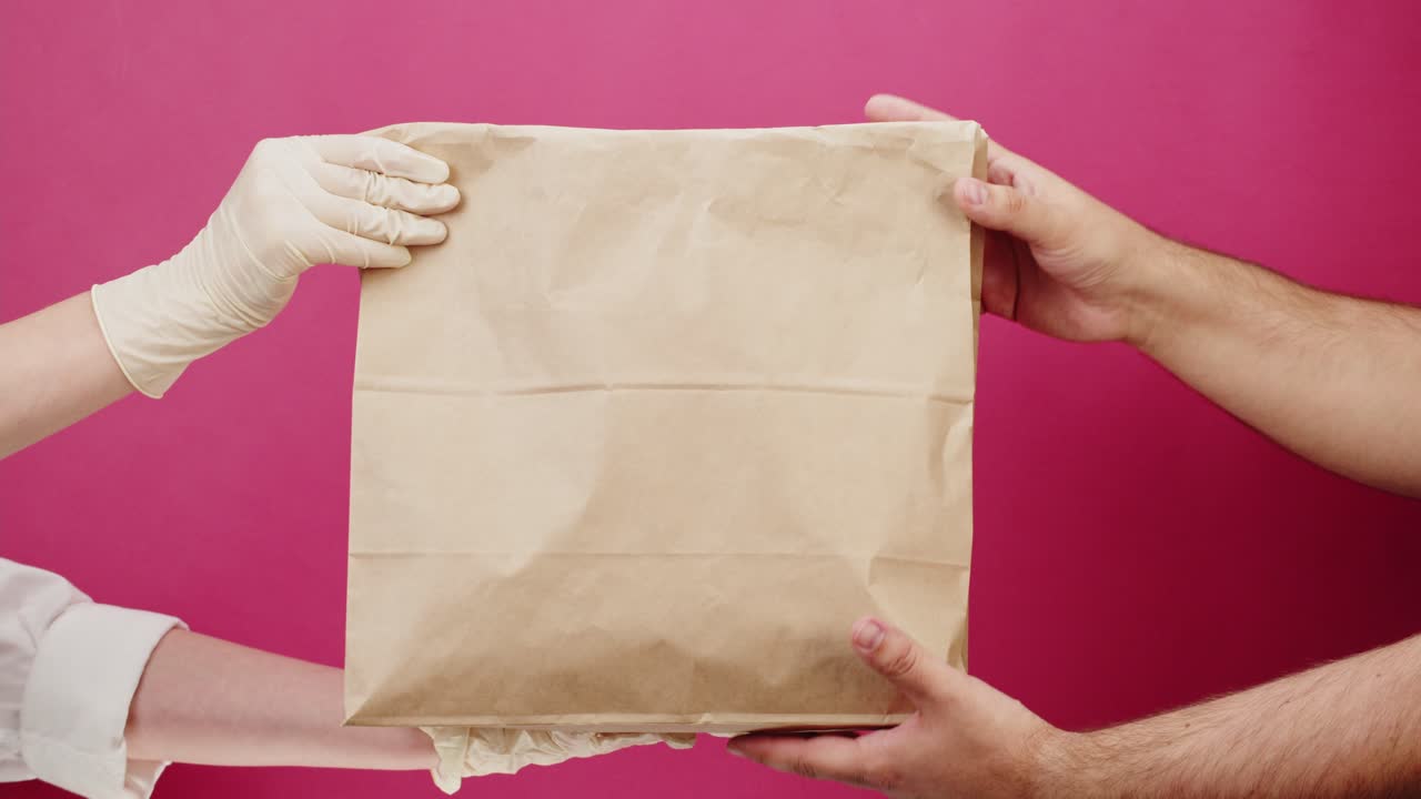 Person in Protective Gloves Handing Over Paper Bag