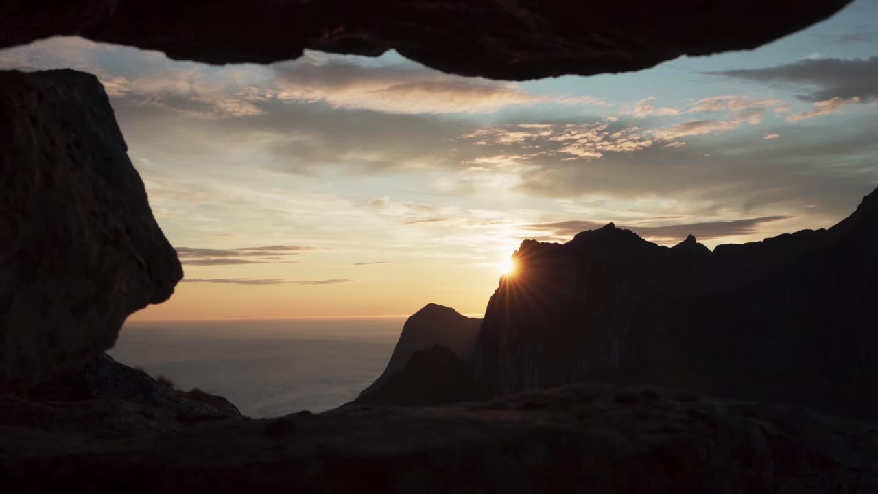 mirando la puesta de sol a través de las grietas de las montañas en hesten, noruega