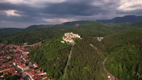 la ciudadela de rasnov sobre la ciudad al atardecer con exuberante vegetación, vista aérea