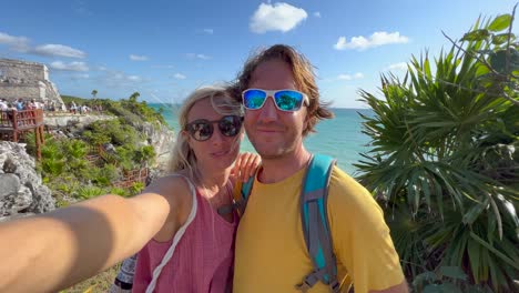 happy couple taking selfie with tulum ruins in mexico.