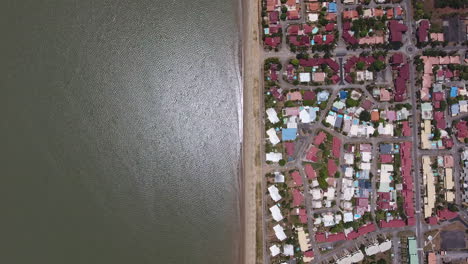 Vertical-drone-shot-of-the-ocean-and-front-beach-neighbourhood-Guiana-sunny-day