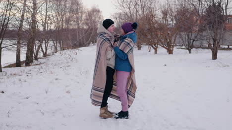 couple wrapped in blanket in snowy park