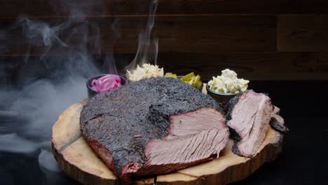 perfectly grilled pork ham on a rustic wooden plate with sides and with a smoking background - tilt-up medium shot