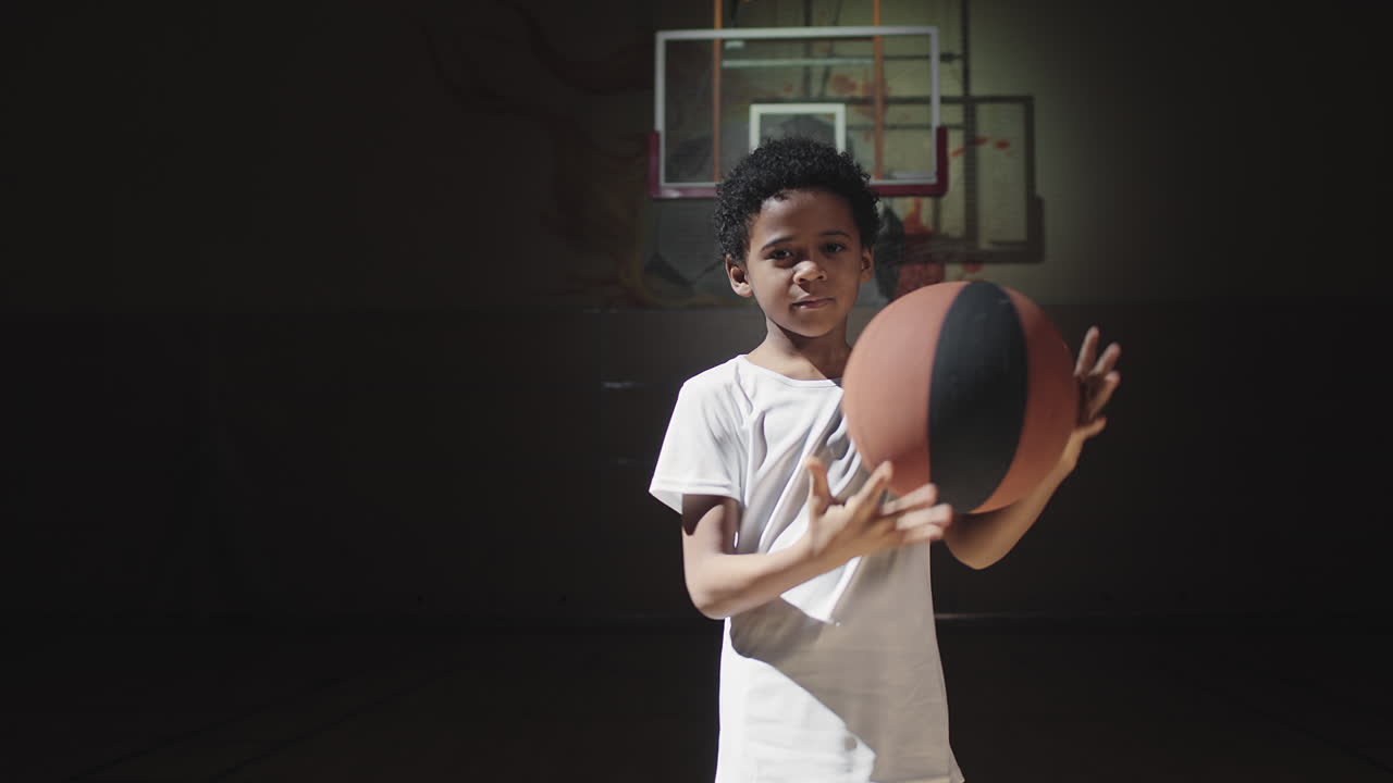 Portrait of Boy Standing in Spotlight on Basketball Court