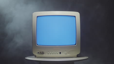 vintage television with blue screen in smoky background