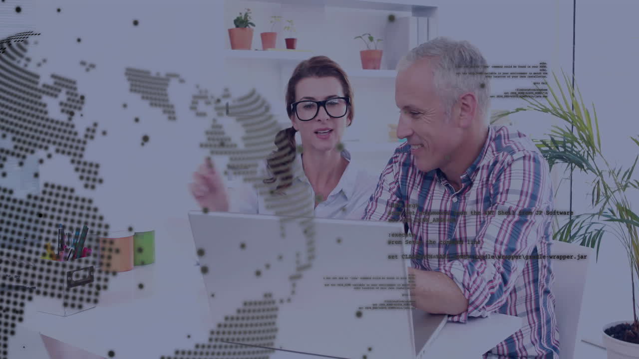 woman reviewing document beside man pointing at laptops in tech office, showing world map overlay