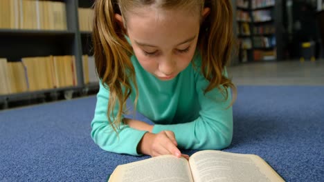 Vista-Frontal-De-Una-Atenta-Colegiala-Caucásica-Leyendo-Un-Libro-En-La-Biblioteca-De-La-Escuela-4k