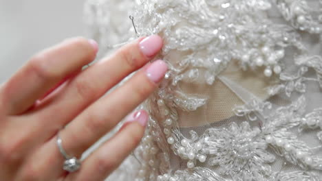 close-up fashion designer for brides in his studio pins needles lace wedding dress. seamstress creates an exclusive wedding dress. secure with pins and needles outline. small private business