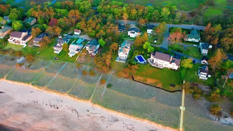 aerial drone video shows a peaceful maine beach house. prime coastal real estate with sandy yard, ocean view, patio, and big windows. relaxing waterfront lifestyle on the beautiful atlantic shore.