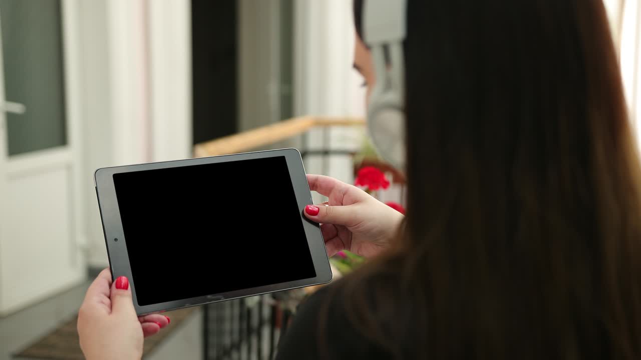 Mockup woman hands holding tablet pc with blank white white in-ear headphones.