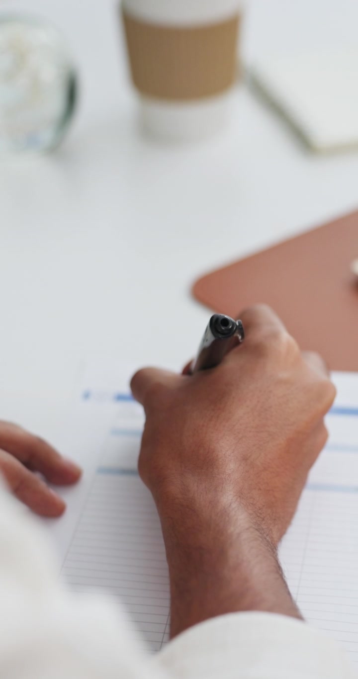Person Writing on Paper Document at Office Desk