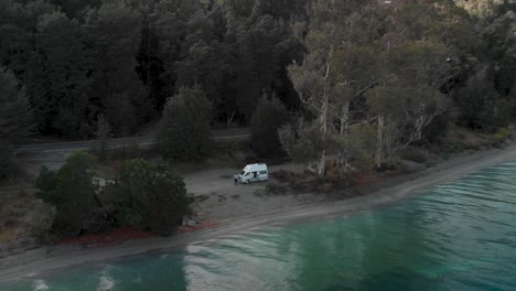 slowmo - campervan on beach beautiful blue lake wakatipu, queenstown, new zealand and trees scenery during fall autumn - aerial drone