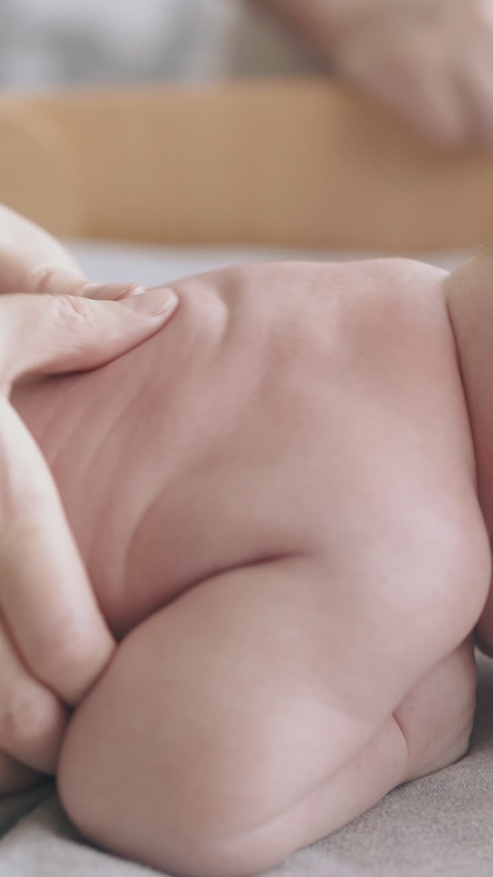professional pediatrician practices hypertonus back massage on lying on stomach newborn and takes baby in arms closeup
