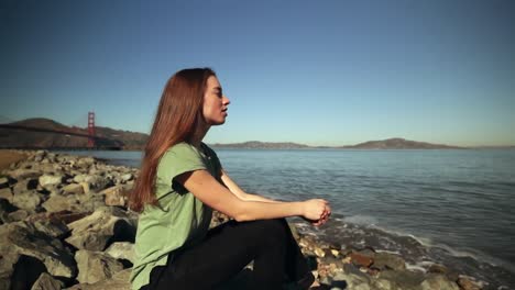 Mujer-Sentada-Sobre-Las-Rocas-Al-Lado-Del-Puente-Golden-Gate.