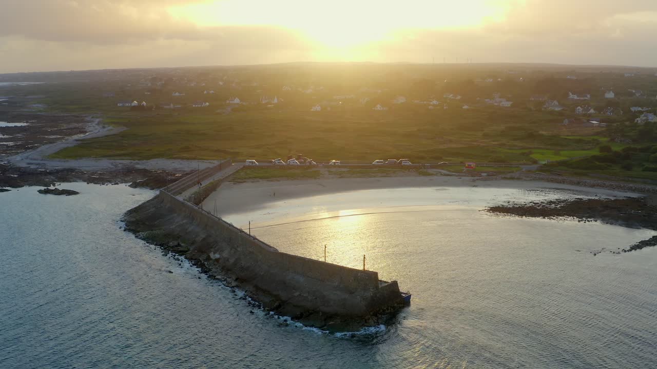 Aerial dolly shot descending to Spiddal's East Pier, beautifully backlit by a stunning sunset