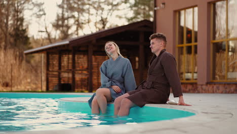 honeymooners are resting in modern spa hotel with outdoor swimming pool young man and woman in gowns