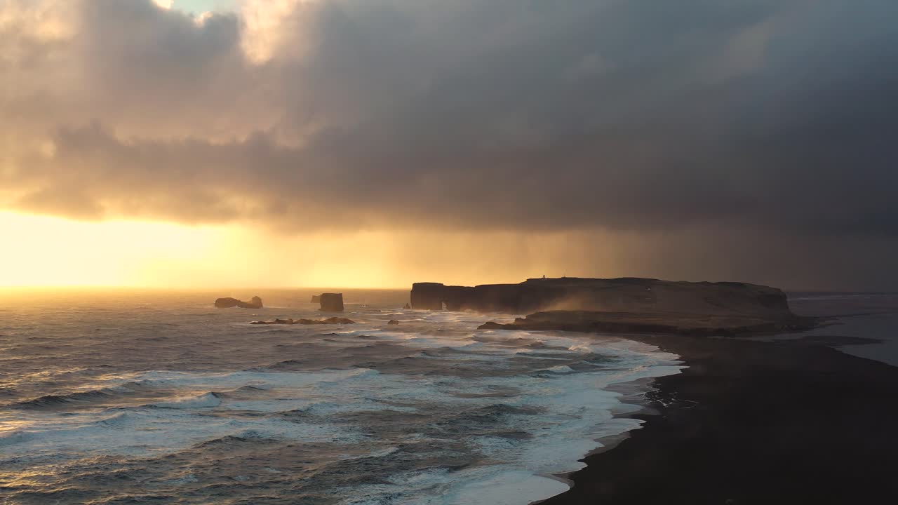 Immersive Aerial Shots of Iceland's Black Sand Beach, Revealing the Power of Waves Against the Sunset Skyline