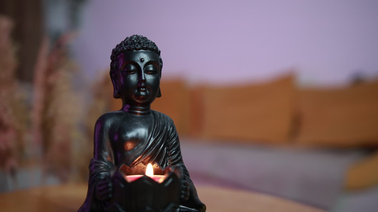 movimiento lento de primer plano de una estatua de buda con una vela en el ambiente acogedor de la sala de estar