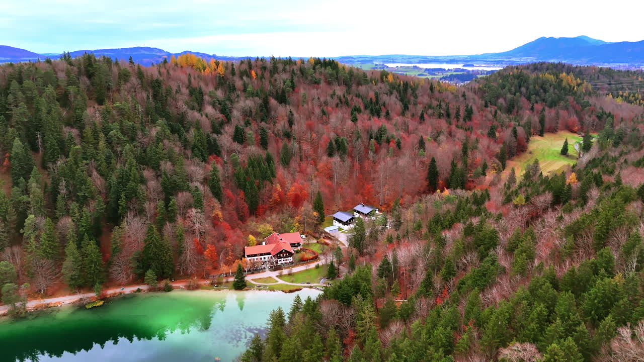 Lakeside village in colorful autumn woods. Small village by a reflective lake set within vivid autumn forested hills