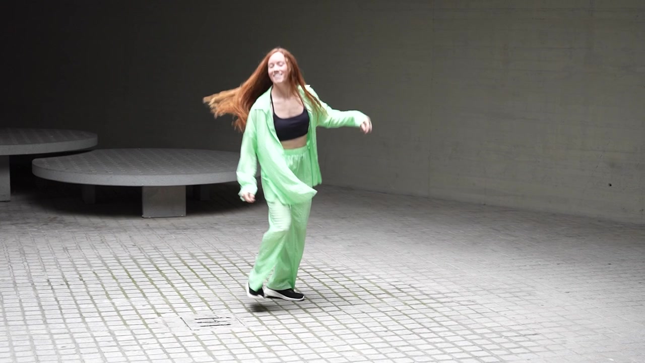 Enthusiastic woman in green outfit performing a dynamic dance routine with confidence and style