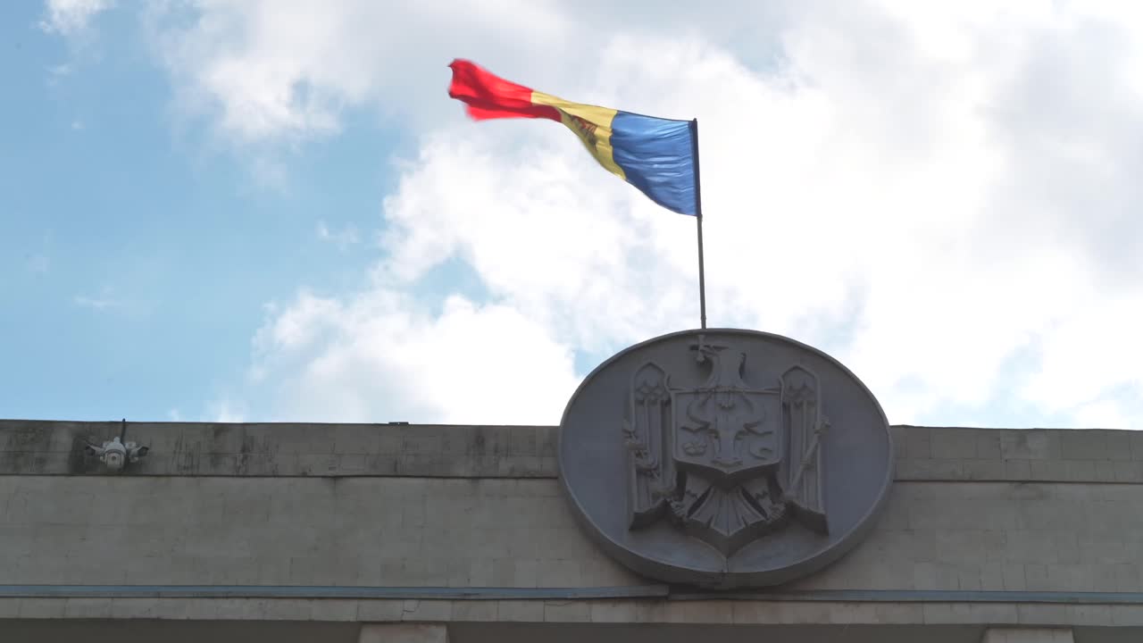 The flag of Moldova waving on top of a building with the sky on the background