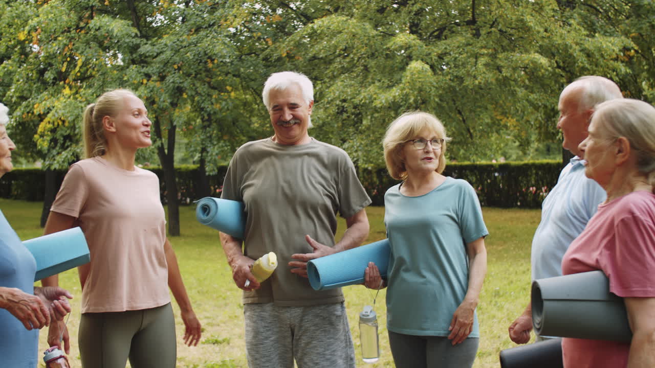 personas mayores felices hablando con una entrenadora en el parque