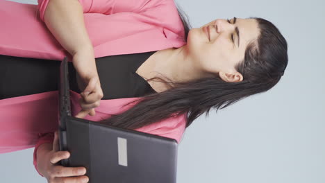 video vertical de una mujer de negocios mirando una computadora portátil con una expresión asustada.