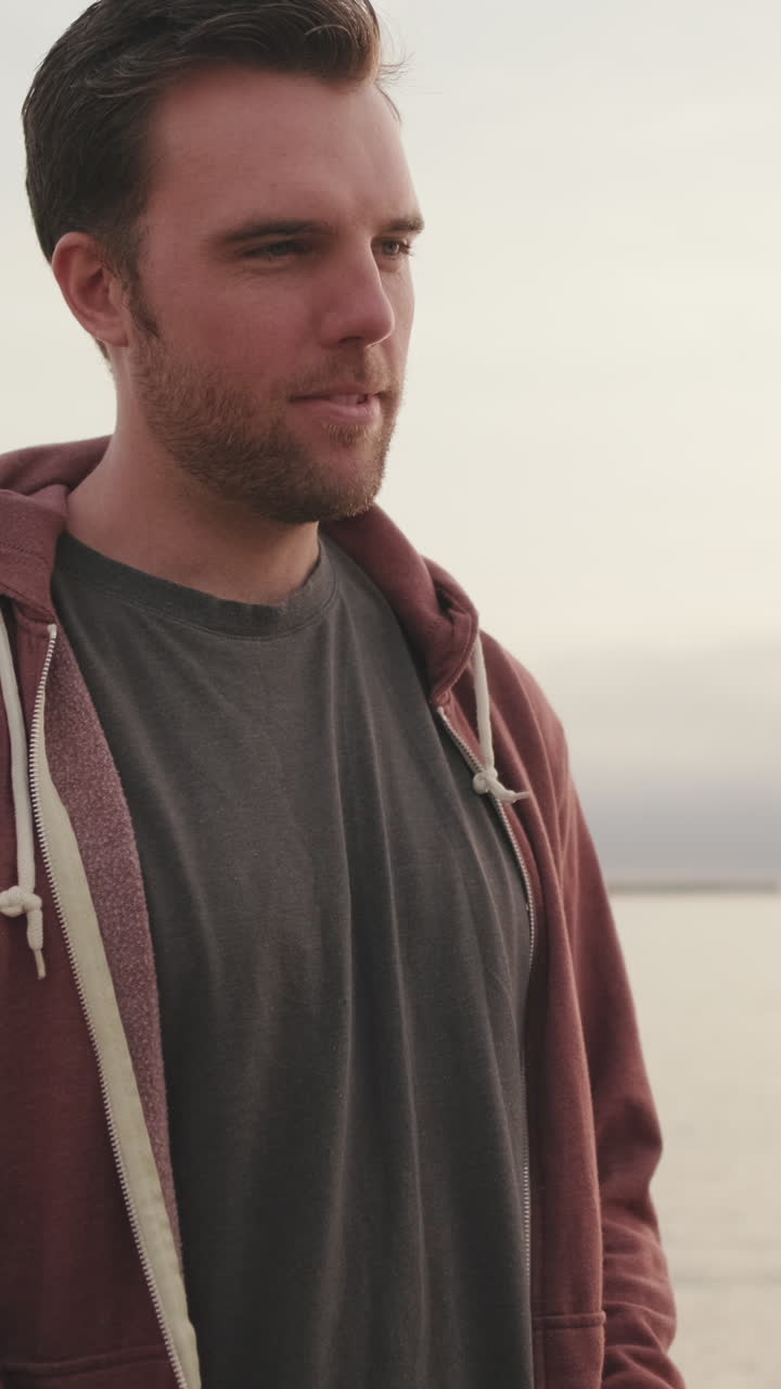 Man with beard wearing hoodie at the beach