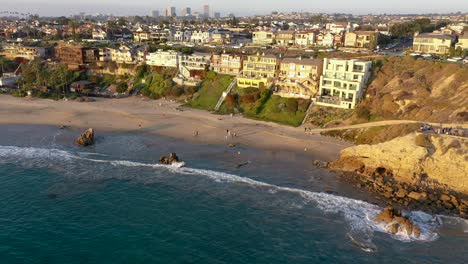 Million-dollar-luxury-homes-overlook-the-crystal-clear-blue-ocean-waters-of-the-Sunny-Southern-California-coast-as-families-play-in-the-sand-and-water