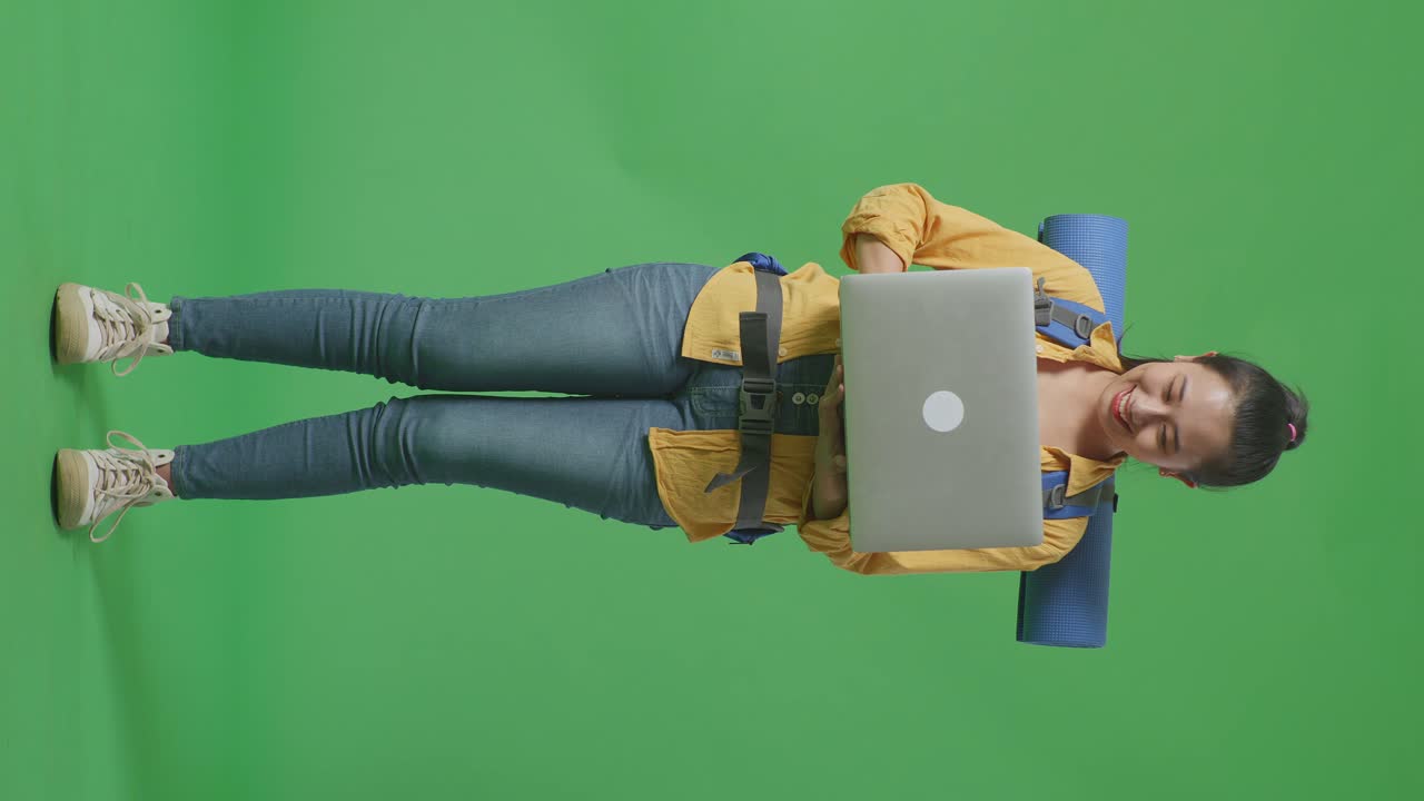 una mujer con una computadora portátil y una mochila emocionada.