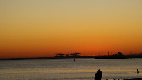 couple silhouetted against sunset at st kilda beach