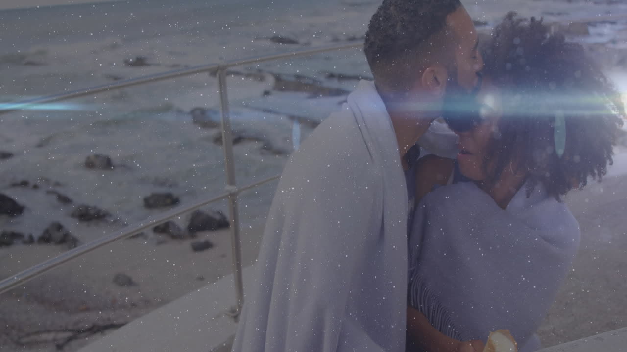 Wrapped in blanket, couple watching ocean with sparkling light animation effects