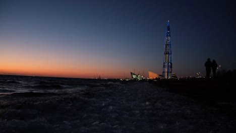 puesta de sol sobre la playa de la ciudad con la torre iluminada